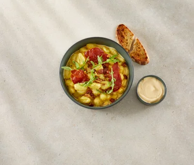 GNOCCHI MED CASTELLO® GNIST, SPRØD PROSCUITTO, RISTEDE MANDLER OG RUCOLA