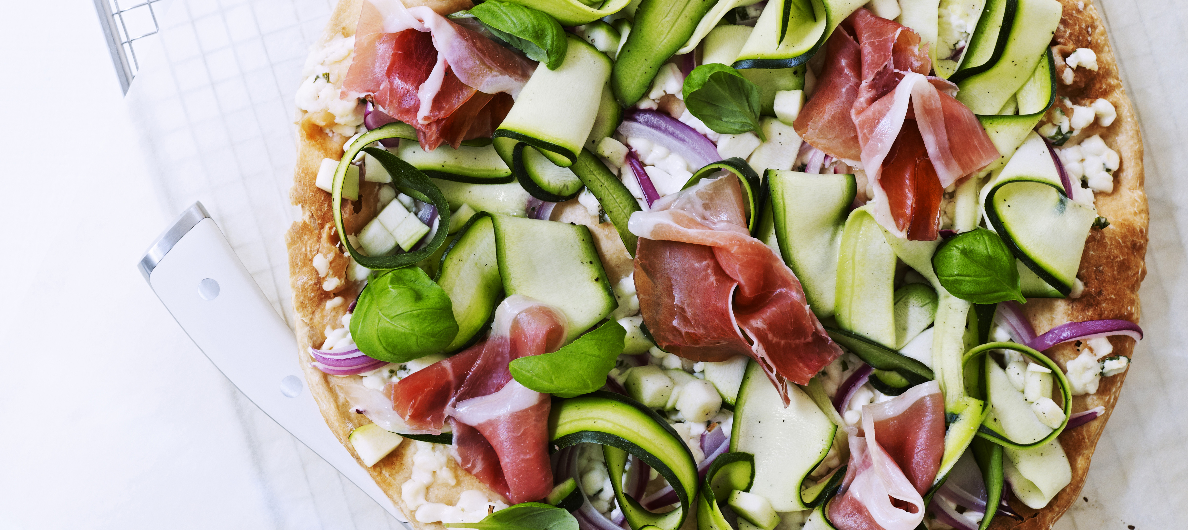 Pizza med hytteost, parmaskinke og basilikum