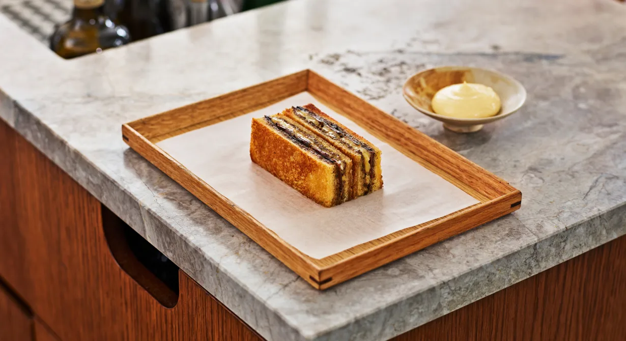 Det här är en lyxig variant på grilled cheese. Osttoasten på briochebröd är välfylld med duxelles på skogschampinjoner, guancale, tryffel och långlagrad Svecia. En len och smakrik ostkräm serveras till. Toastan förvaras färdigmonterad i frysen och sedan läggs sista handen vid beställning. Enkelt och smidigt för barpersonalen!