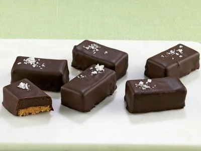Klassisk utanpå men med trendiga amerikanska godissmaker inuti. På krispig jordnötsbotten ligger en kaffetryffel doppas i mörk choklad och toppad med flingsalt.