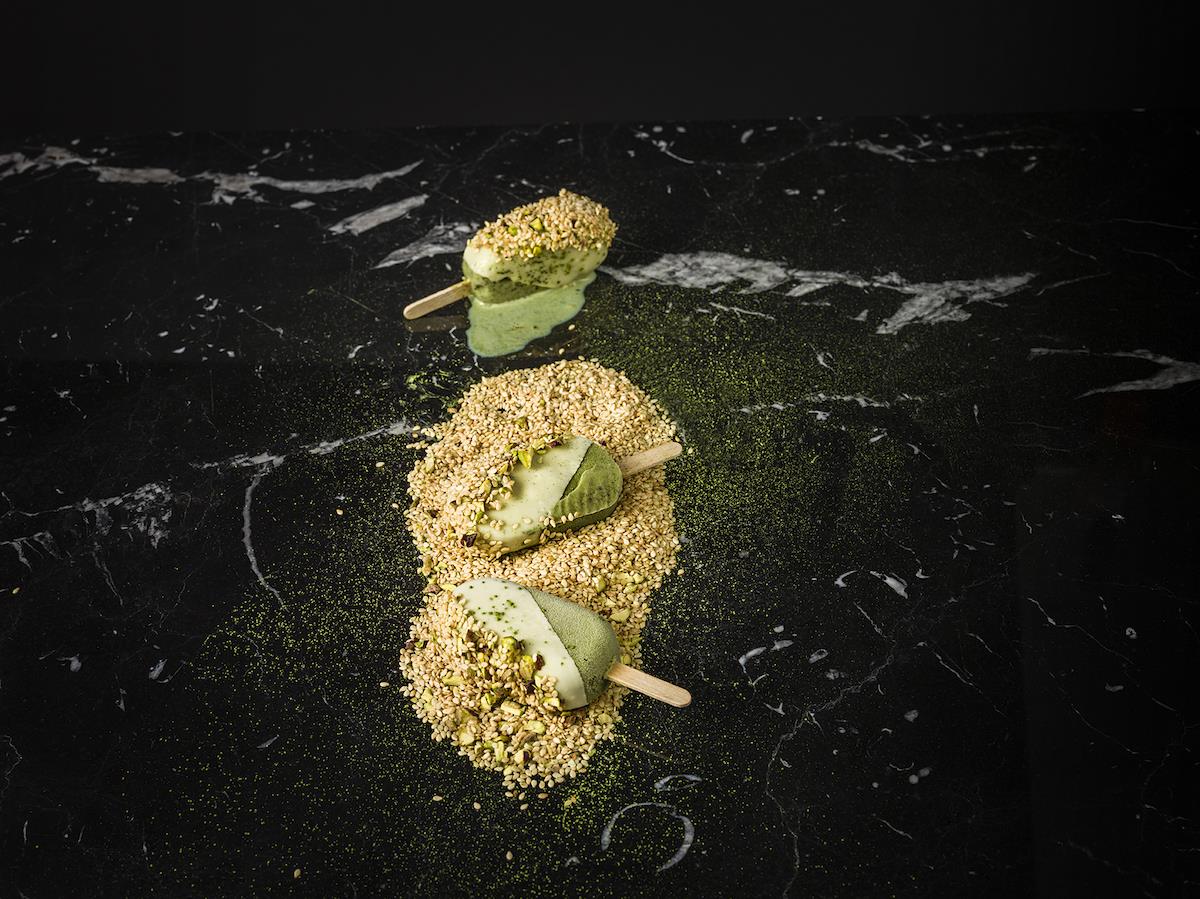 Matchaglasspinne med ingefära och lime doppad i vit choklad, pistage och sesam