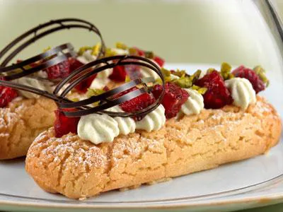 Trendig éclair i ny design fylld med fluffig pistagegrädde och hallongelé.
