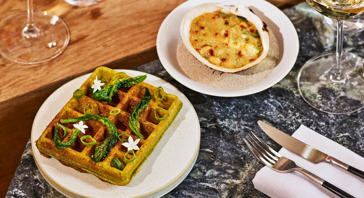 En våffla smaksatt med ramslök serverad med gratinerade hjärtmusslor med cocobönor är en perfekt att erbjuda bargästerna på våren, när ramslök är i säsong. Allt är förberett och behöver bara värmas, gratineras och garneras vid beställning.