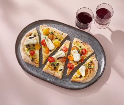 Pinsa with mascarpone, tomatoes, brie, and olives