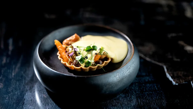 Taart gevuld met gebakken champignons en wortelen, gegarneerd met gebruinde boter uit de sifon