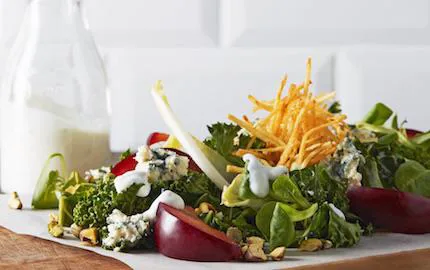 Mättande sallad med krämig dressing som du lägger på precis innan servering. En härlig kombo med nyttig grönkål, söta plommon och ädelost. Allt toppat med läckert friterade potatisstrimlor.