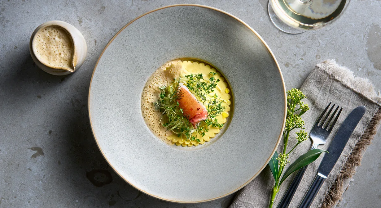 Öppen hummerravioli med fräst kål och en len hummersås med smör toppas med strimlad färsk kål och en bit färsk hummer. Lyxig förrätt eller mellanrätt som platsar på de flesta menyer när hummern är i säsong på hösten.