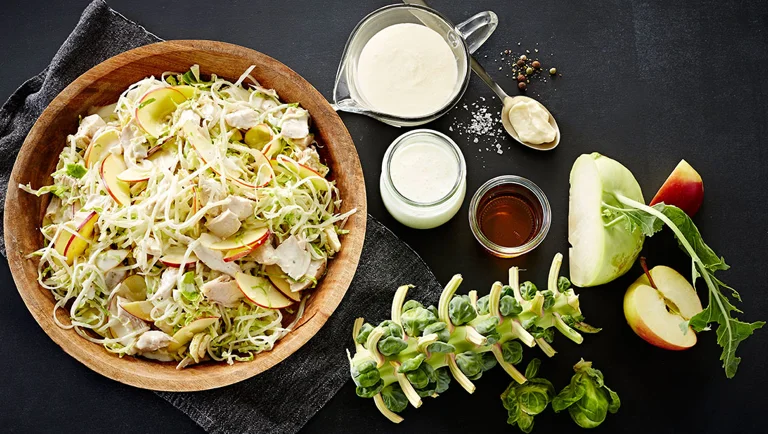Salat af rosenkål, æbler, kylling og glaskål med kærnemælksfløde