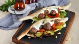 Samoon bread with cream cheese, kofta meatballs, fresh salad leaves, pickled cucumbers and pine nuts