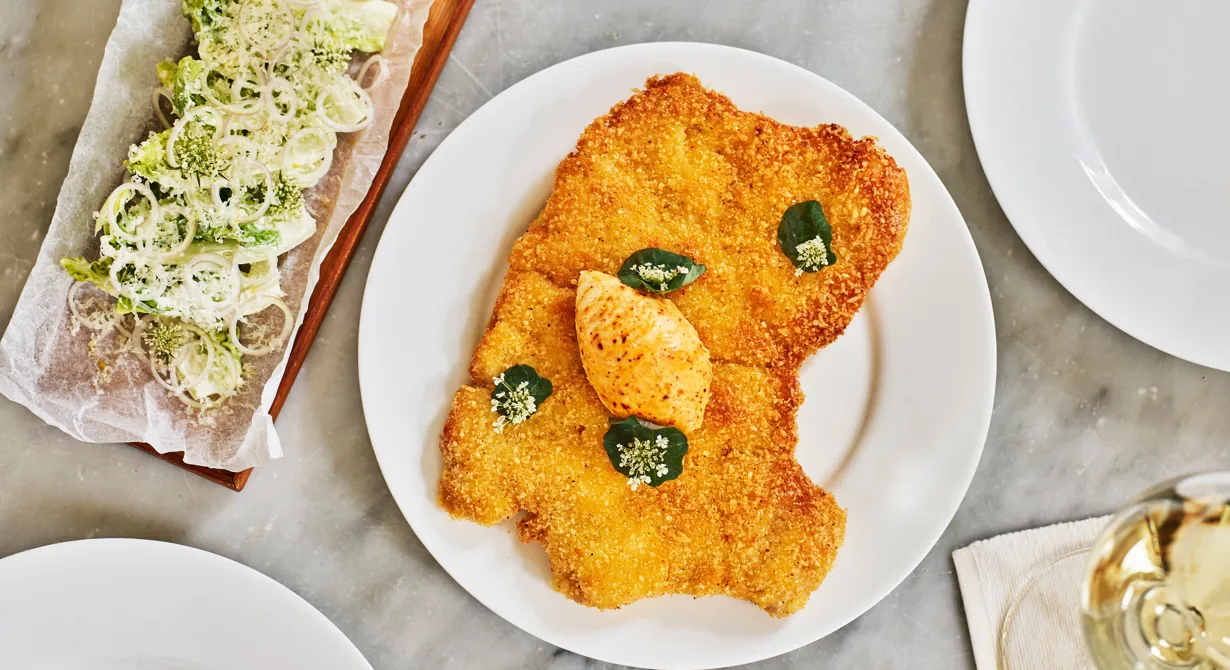 Frasig schnitzel med ost- och ansjovissmör är en klassisk rätt att erbjuda gästerna i baren. Kvibille Cheddar ger smak till schnitzeln, kryddsmöret och salladen, som serveras till. En schnitzel serveras som sharingrätt till två personer.