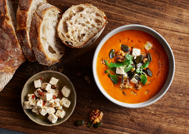 Tomatsoppa toppad med vitost, rostade nötter och färsk oregano