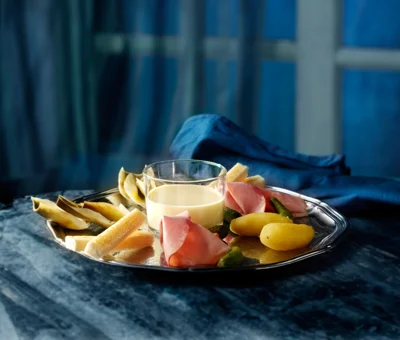 Fondue au fromage avec artichauts, jambon fumé et cornichons